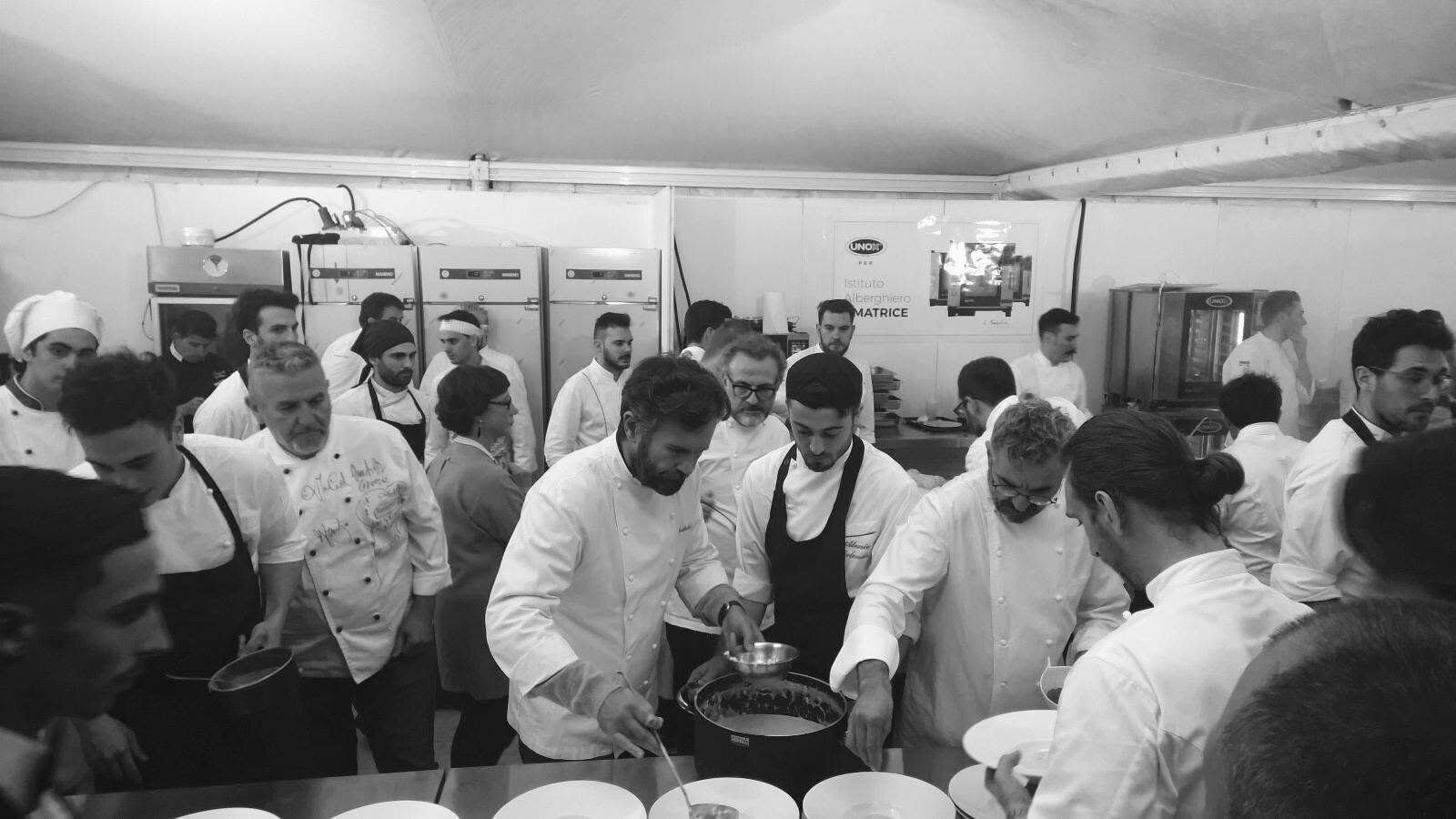 La grande cucina comune allestita in tenda, decine di chef al lavoro fianco a fianco