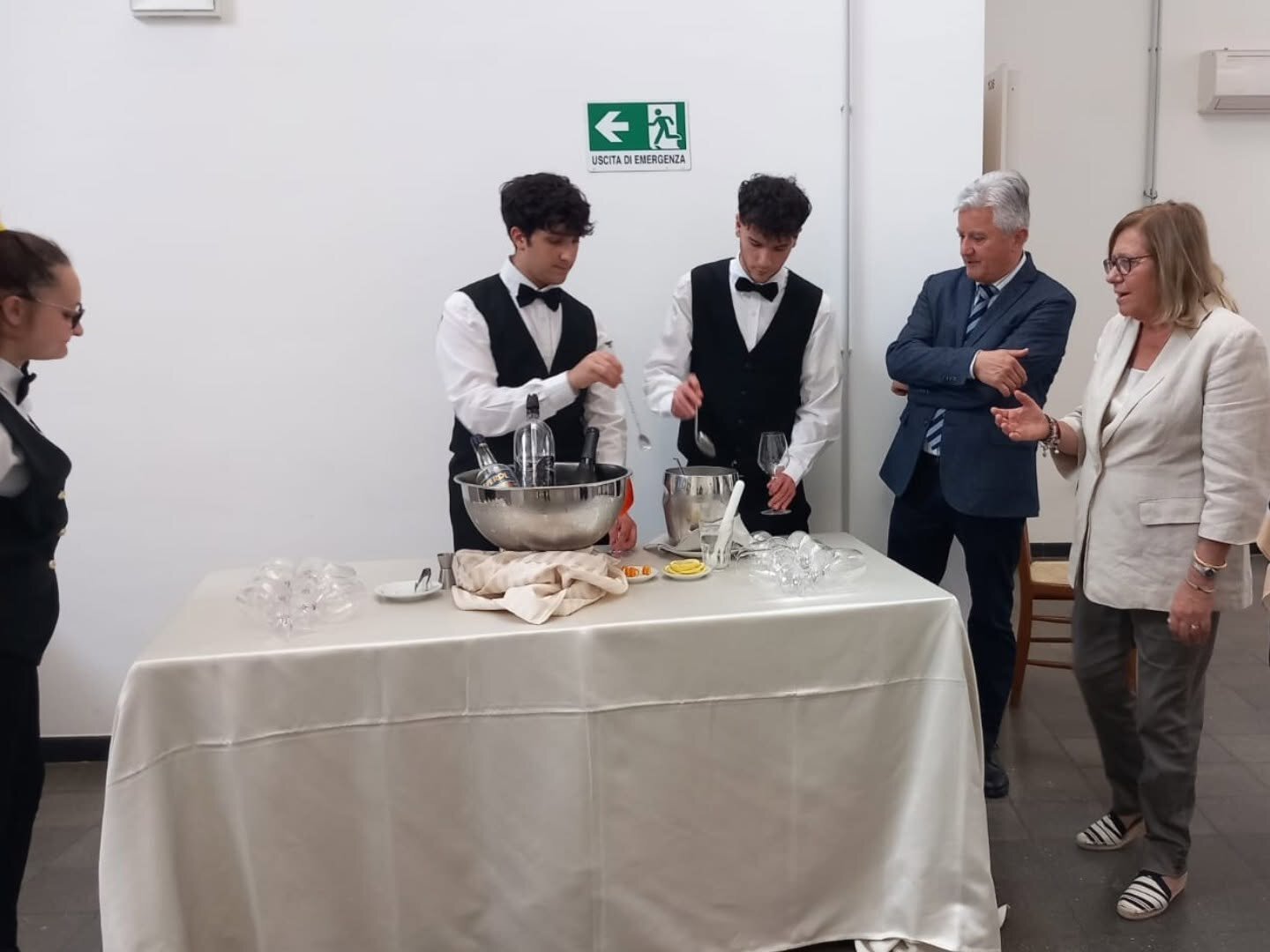 Due allievi di sala preparano una miscelazione al bancone davanti agli ospiti