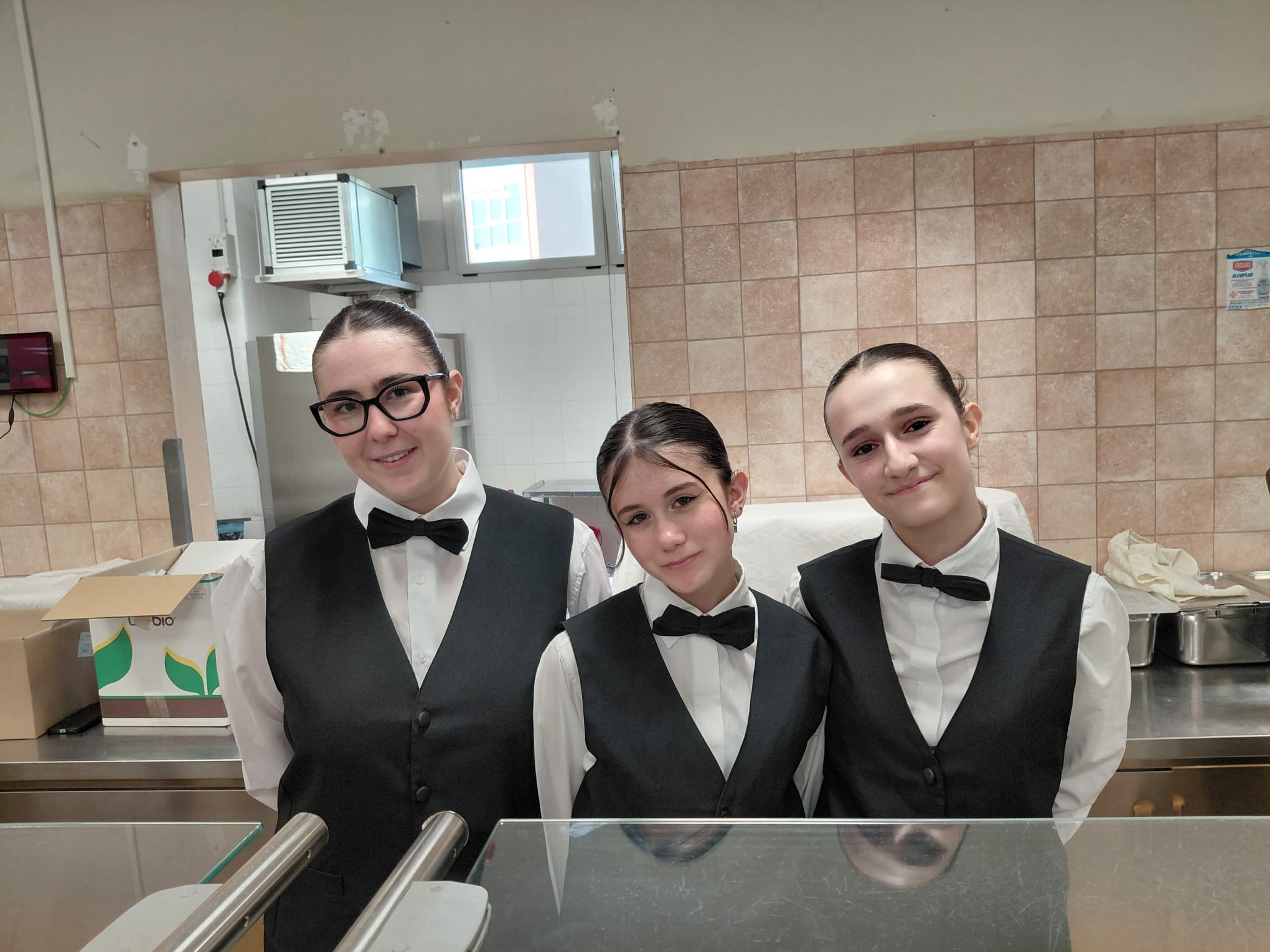 Tre studentesse in divisa di sala dietro il bancone di servizio