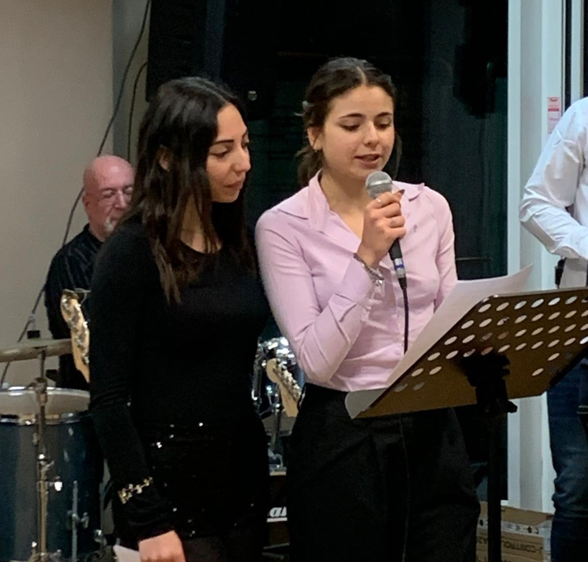 Due studentesse cantano al microfono