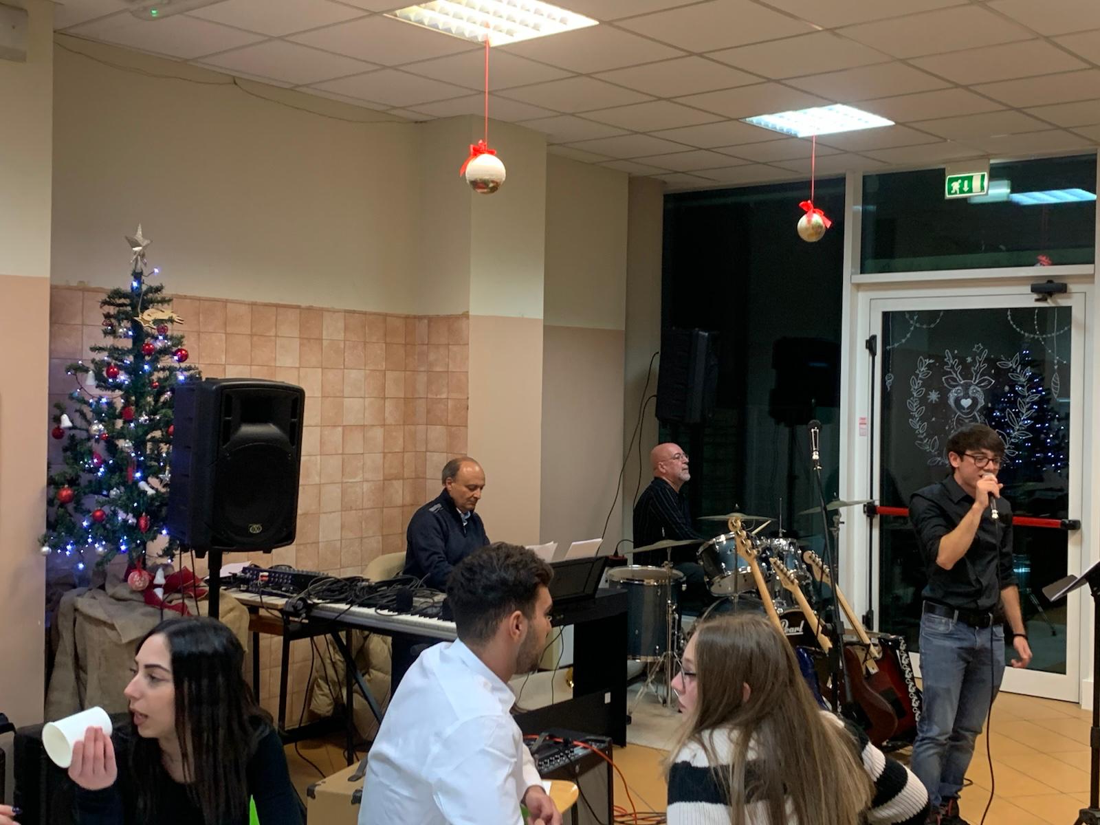 Panoramica del palco con albero di Natale, tastiera, batteria e cantante